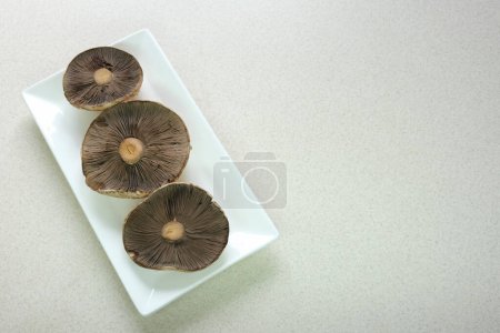 Téléchargez les photos : D'énormes chapeaux de champignons Agaricus reposent sur la table. Des plaques sombres sont visibles. Champignons sont préparés pour la préparation de délicieux plats. Photo de haute qualité - en image libre de droit