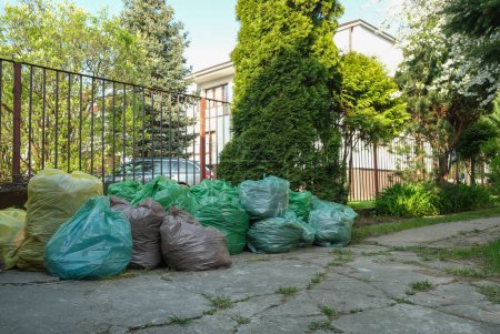 Téléchargez les photos : Many colorful bags of garbage lie near the fence on the street. High quality photo - en image libre de droit