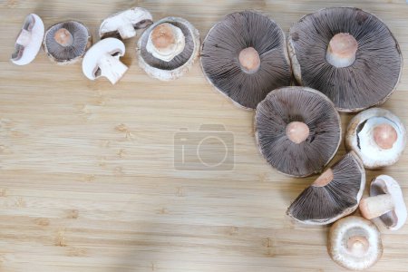 Téléchargez les photos : Des champignons Agaricus entiers et coupés se trouvent sur la table. Champignons de différentes tailles. Contexte. Un endroit pour votre texte. Photo de haute qualité - en image libre de droit