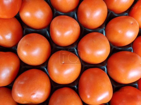 Téléchargez les photos : A background of red tomatoes. Ripe vegetables lie in special cells. High quality photo - en image libre de droit