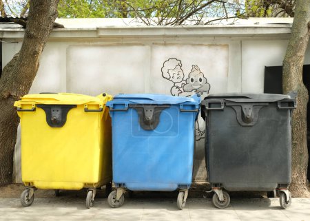 Téléchargez les photos : Poland, Warsaw, 05/04/2022. Three large multi-colored plastic garbage cans stand on the street. High quality photo - en image libre de droit