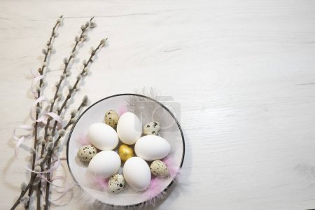Téléchargez les photos : Composition de Pâques d'œufs de poulet et de caille dans une assiette sur la table, décorée de branches de saule. Photo de haute qualité - en image libre de droit