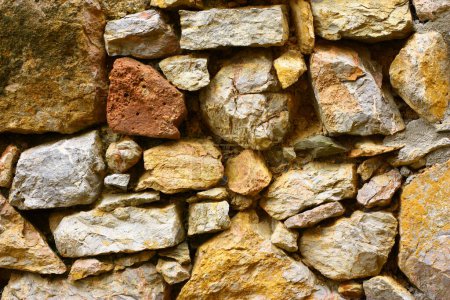 Téléchargez les photos : Un mur de pierres de différentes tailles et couleurs. Photo de haute qualité - en image libre de droit