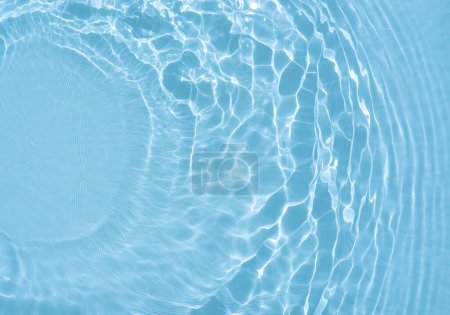 Téléchargez les photos : Belle image de fond originale en teinte bleue pour un travail créatif ou un design sous forme de surface d'eau avec des ondes circulaires divergentes, un jeu de lumière et d'ombre et un espace pour le texte. Texture de l'eau. - en image libre de droit