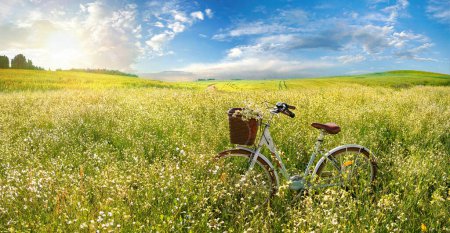 Photo for Beautiful spring summer natural landscape with a bicycle on a flowering meadow against a blue sky with clouds on a bright sunny day. - Royalty Free Image