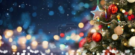 Téléchargez les photos : Beau fond de Noël avec un arbre de Noël orné sur un fond bleu soir avec des lumières luisantes floues et beau bokeh. - en image libre de droit