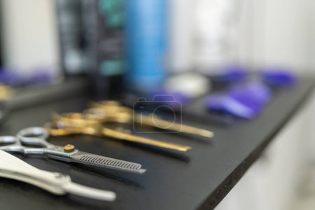 Téléchargez les photos : Gros plan et mise au point sur une planche avec ciseaux et outils dans un salon de coiffure - en image libre de droit