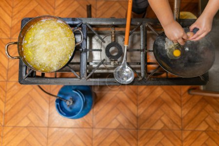 Vue de dessus d'un chef préparant une omelette dans un poêle dans une cuisine commerciale modeste