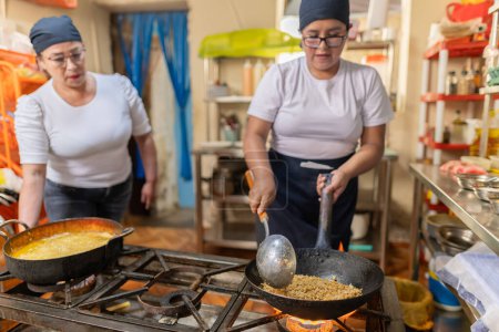 Cocinera profesional y asistente preparando arroz Chaufa en un restaurante peruano