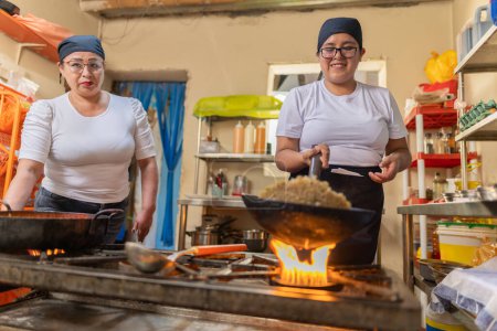 Cocinero peruano preparando arroz Chaufa en una cocina comercial junto a un colega