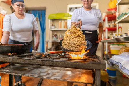 Expertise chef sacando arroz de una sartén mientras prepara Chaufa, un plato tradicional peruano