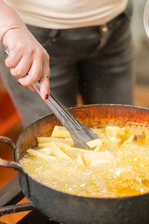Vertikale Nahaufnahme einer Köchin beim Braten von Kartoffeln in einem Restaurant