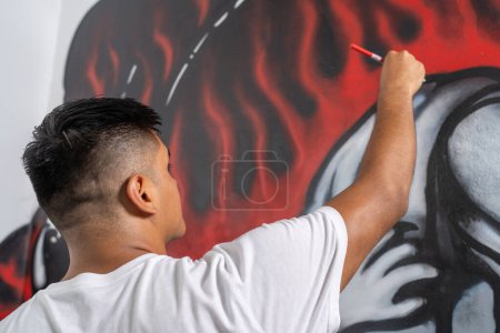Rear view of a muralist touches up details and lines of a mural with a small brush