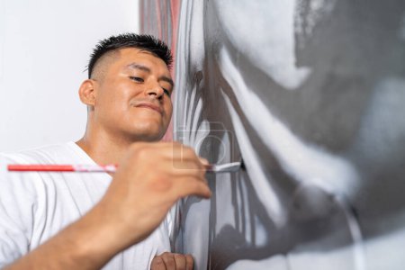 Konzentrieren Sie sich auf einen lächelnden Maler, der Linien von Hand mit dem Pinsel auf ein neues Wandbild malt