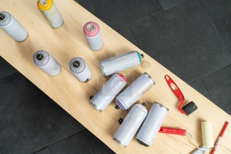 Aerosols of different colors on a wooden table of a muralist workshop