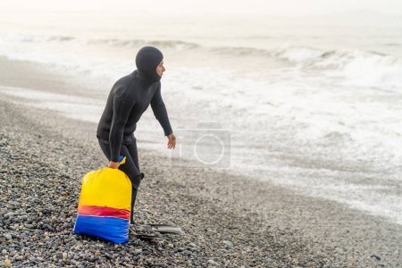 Pescador latino sosteniendo una bolsa con red y piedras listo para pescar en la playa