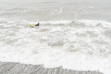 Foto vista amplia con espacio de copia de un pescador en traje de neopreno nadando en el mar