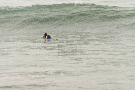 Photo for Wide view photo with copy space of a fisherman in wetsuit fishing inside the water using net - Royalty Free Image