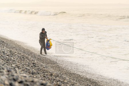 Fotografía horizontal con espacio de copia de un pescador con aletas y traje de neopreno trabajando con cuerda y red para pescar