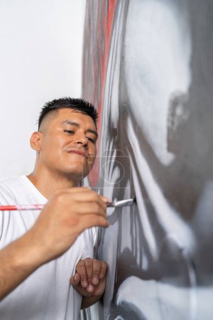 Foto vertical de un artista preciso retoca los detalles de un mural con un pincel