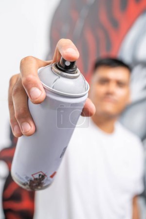 Vertical photo with focus on a finger of a muralist pressing a paint spray