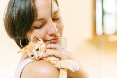 A tender moment of affection as a woman gently holds her kitten, their close bond evident in their embrace.