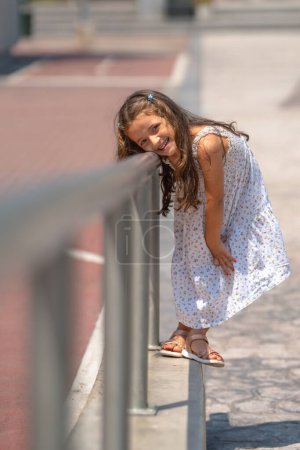 Foto vertical con enfoque en una linda chica recibiendo respaldo cansado a la escuela después de las vacaciones