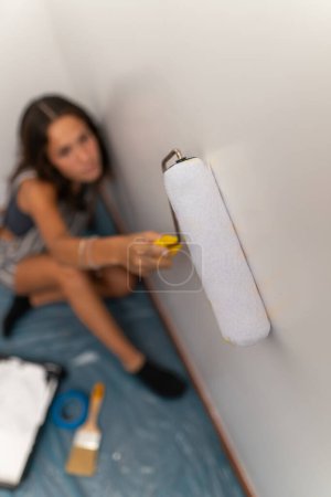 Mujer joven casa de mudanza pintando las paredes usando rodillo de pintura