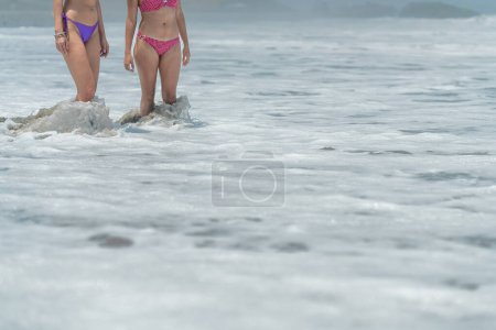 Teil von zwei unkenntlich gemachten Frauen im Bikini ins Meerwasser