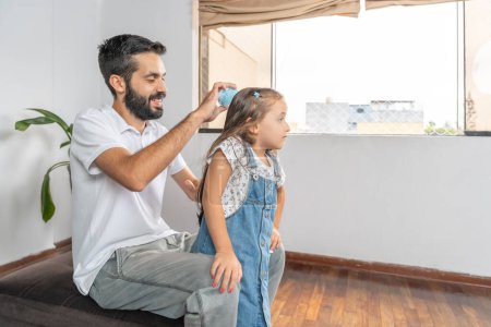 Père tendre brossant les cheveux d'une fille assise à la maison