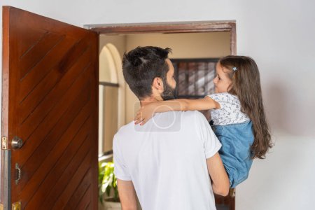 Vista trasera de un padre latino acompañando a su hija a la puerta en su primer día de escuela