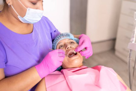 Ein Zahnarzt in Schutzkleidung führt eine gründliche mündliche Untersuchung an einem Patienten in einer Zahnarztpraxis durch