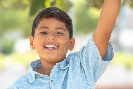 Portrait d'un écolier heureux dans un parc public souriant à la caméra portant l'uniforme