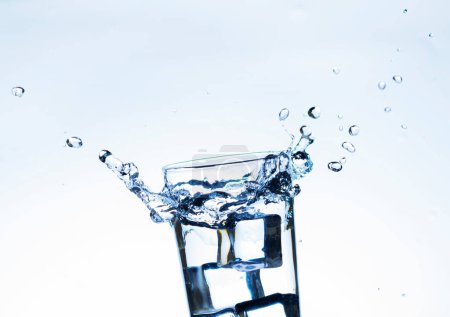 Téléchargez les photos : L'image de verser de l'eau potable, dans un verre, qui permet de se sentir rafraîchi sur fond blanc flou, Eau éclaboussante, Eau pétillante - en image libre de droit