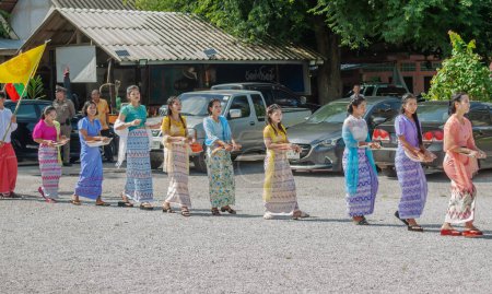Foto de SURATTANI, TAILANDIA - NOV. 06, 2023: Las mujeres birmanas se visten con trajes nacionales. Ven a participar en el festival de Kathin durante el final de la Cuaresma budista para los hermanos y hermanas birmanos en Tailandia. - Imagen libre de derechos