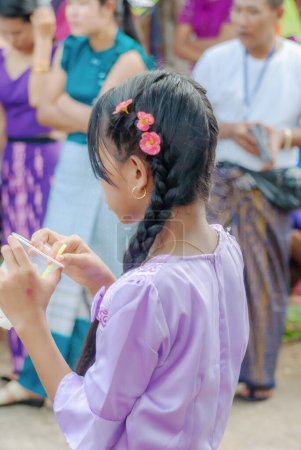 Foto de SURATTANI, TAILANDIA - NOV. 06, 2023: Vestido de niña birmana con trajes nacionales. Ven a participar en el festival de Kathin durante el final de la Cuaresma budista para los hermanos y hermanas birmanos en Tailandia. - Imagen libre de derechos