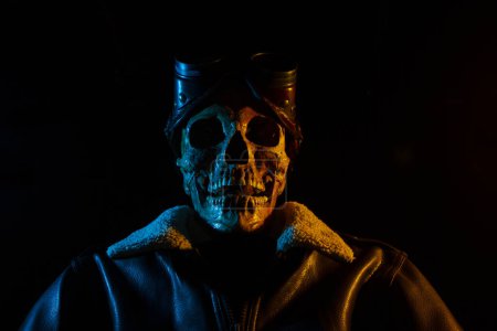 Photo for Skull with leather jacket and steampunk goggles. Aviator costume. Colored light - Royalty Free Image