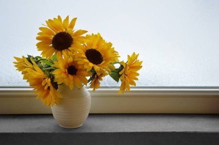Téléchargez les photos : Tournesols frais en vase sur le rebord de la fenêtre. Nature morte festive d'automne avec espace de copie. - en image libre de droit