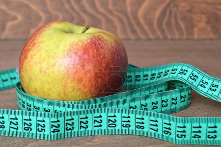 Photo for Apple and measuring tape on wooden background. diet and weight loss concept. - Royalty Free Image