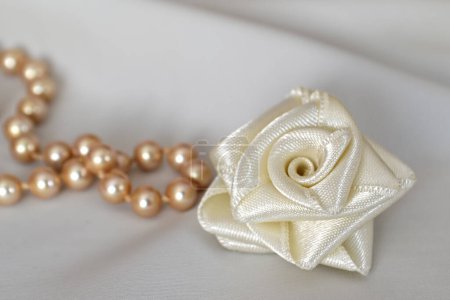 Photo for Pearl necklace and textile rose decoration on the white background, wedding and gift card - Royalty Free Image
