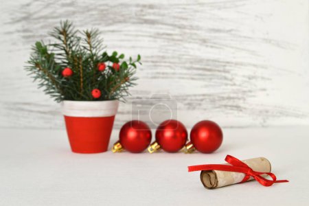 Téléchargez les photos : Décorations de Noël sur un fond en bois blanc. Pot avec brindilles d'épinette, boules rouges brillantes et note de papier vintage - en image libre de droit