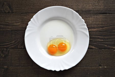 Téléchargez les photos : Deux œufs cassés dans le plat en céramique blanche - en image libre de droit