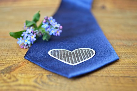Photo for Blue necktie decorated with heart symbol and blue flowers on wooden background - Royalty Free Image