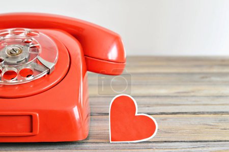 Téléchargez les photos : Téléphone rétro rouge et décoration coeur sur fond bois - en image libre de droit
