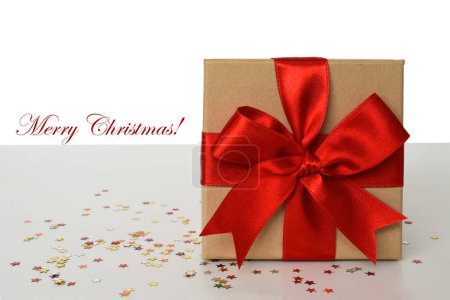 Photo for Wrapped gift box with red ribbon and confetti on white background. Merry Christmas card template - Royalty Free Image
