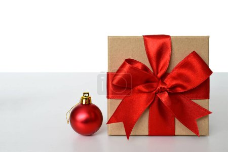 Foto de Regalo de Navidad con cinta roja y bola brillante roja sobre fondo blanco - Imagen libre de derechos