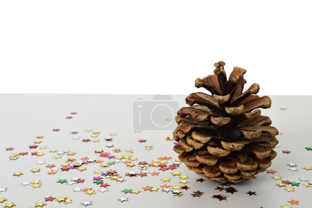 Foto de Composición navideña de cono de pino y confeti colorido sobre fondo blanco. - Imagen libre de derechos