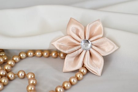 Foto de Collar de perlas y decoración de flores textiles en el fondo blanco, boda y tarjeta de regalo - Imagen libre de derechos