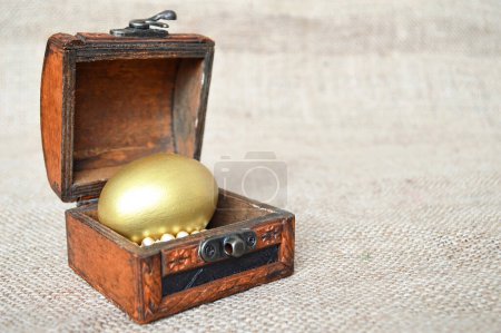 Téléchargez les photos : Oeuf de Pâques antique doré dans une petite poitrine vintage - en image libre de droit