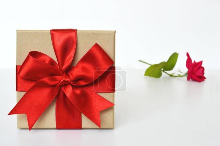 Téléchargez les photos : Coffret cadeau avec ruban rouge et fleur rose sur fond blanc - en image libre de droit